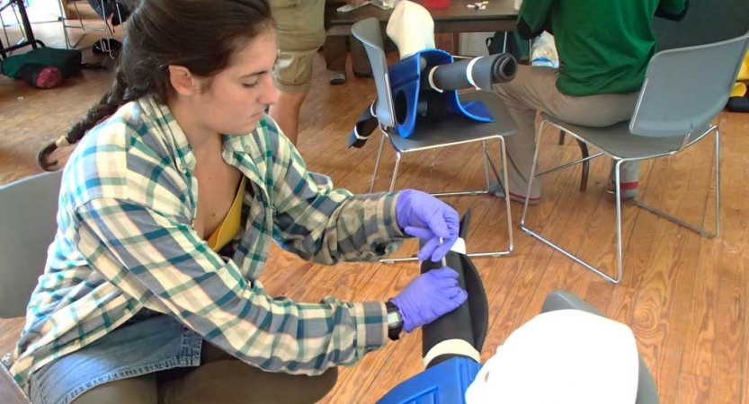 A person participating in a wilderness first aid course practices skills on an ankle. 